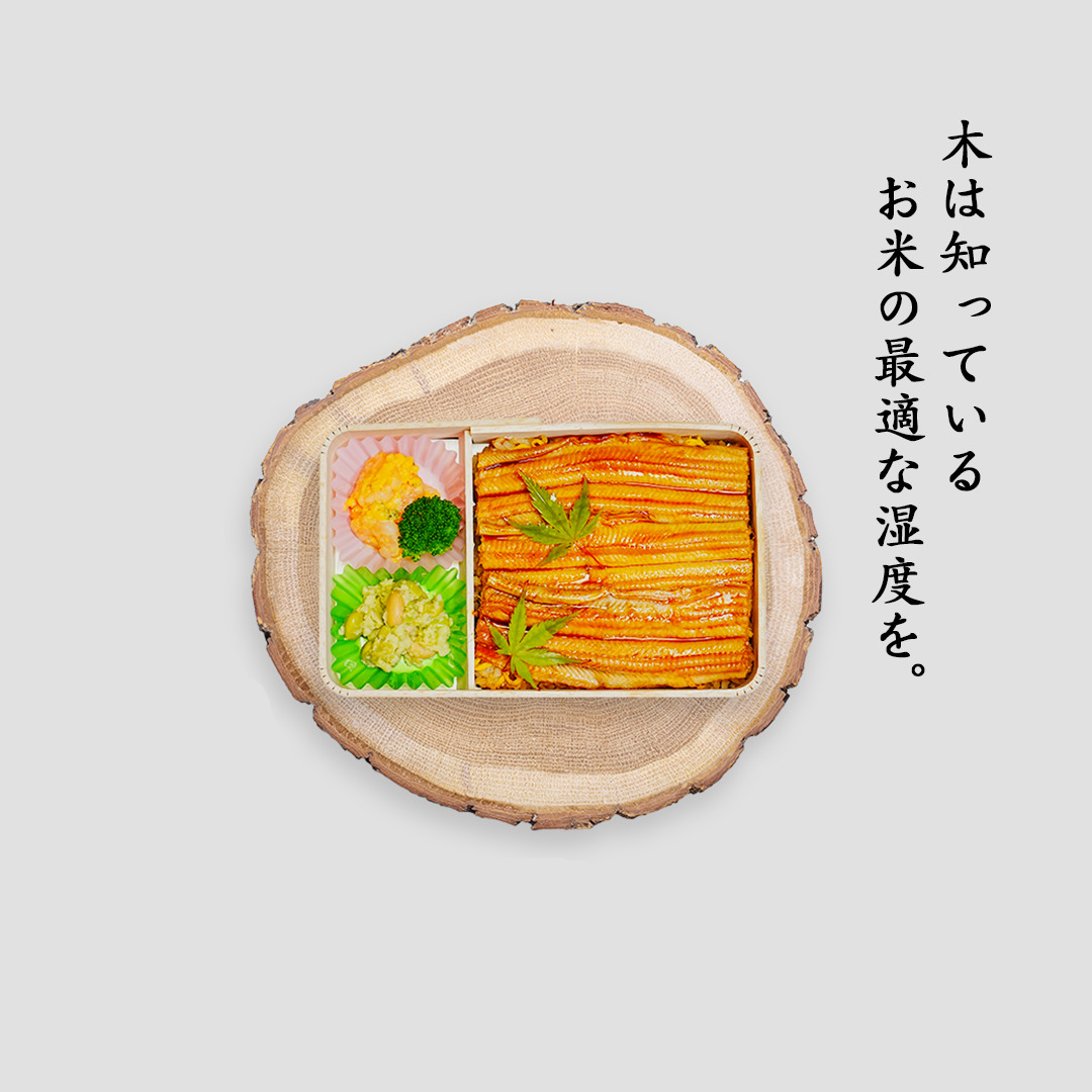 丸太の木に置かれた、木の折箱に入った鰻弁当